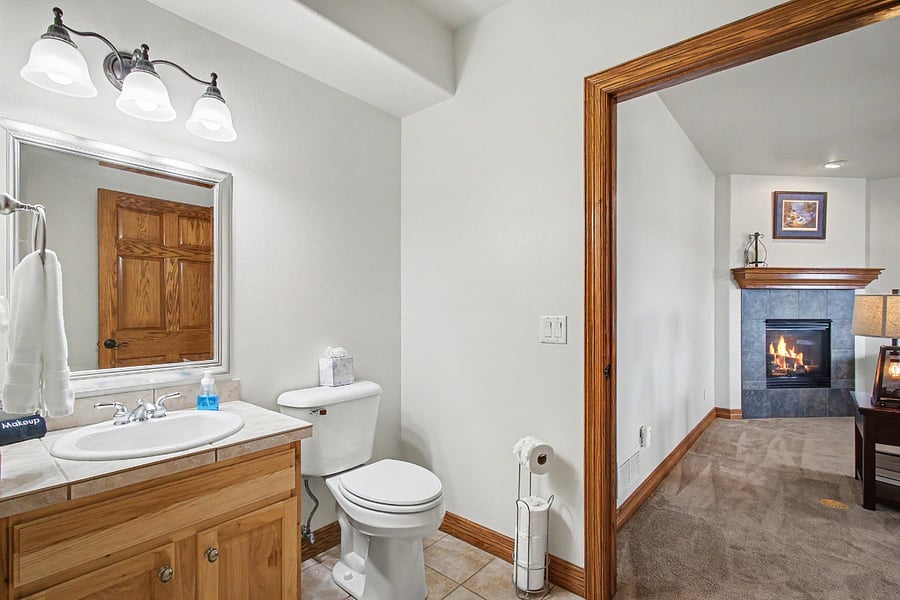 The half bath includes a vanity and toilet, with a connecting door that provides privacy from the separate shower and second vanity area.