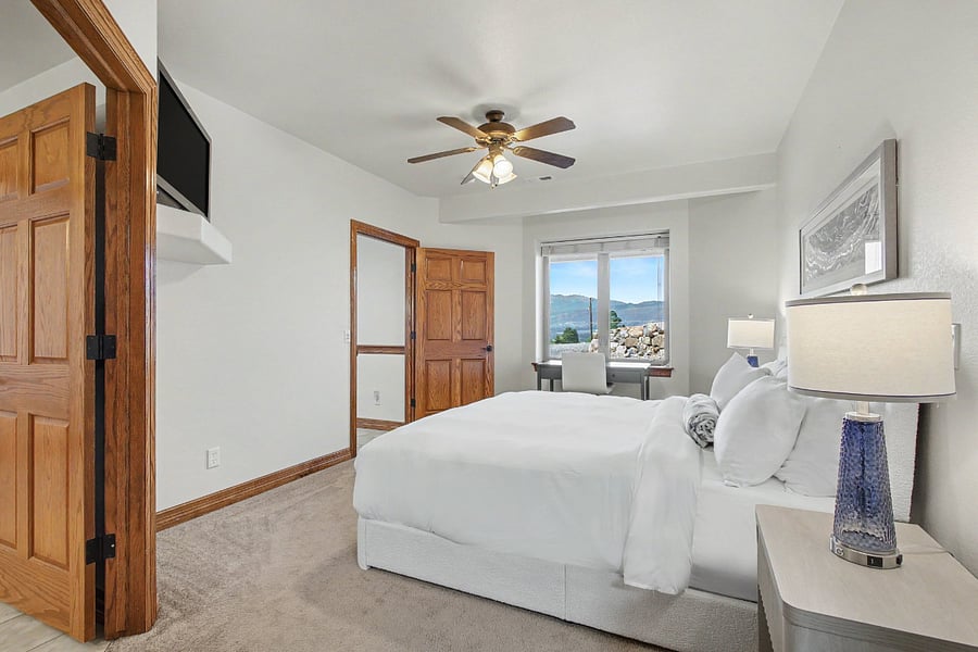 Spacious primary bedroom featuring a dedicated desk, wall-mounted TV, and beautiful views of Pikes Peak and the surrounding mountains.
