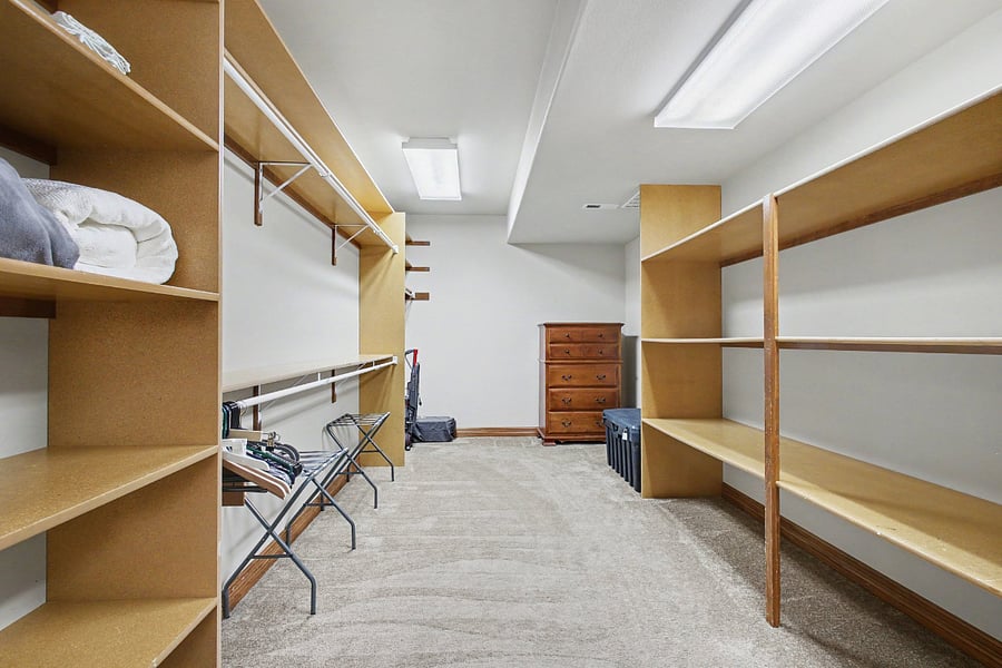 Impressive oversized walk-in closet with extensive built-in shelving and hanging space, offering exceptional storage and enough room to create a private home office or flexible bonus area.