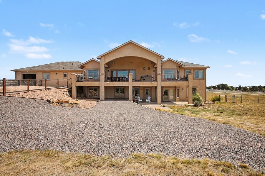 Rear view of the main house showcasing the apartments private entrance, convenient covered parking, and expansive outdoor surroundings.