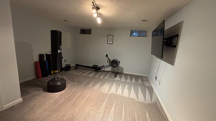 Basement workout space with rowing machine, punching bag, small weights, television