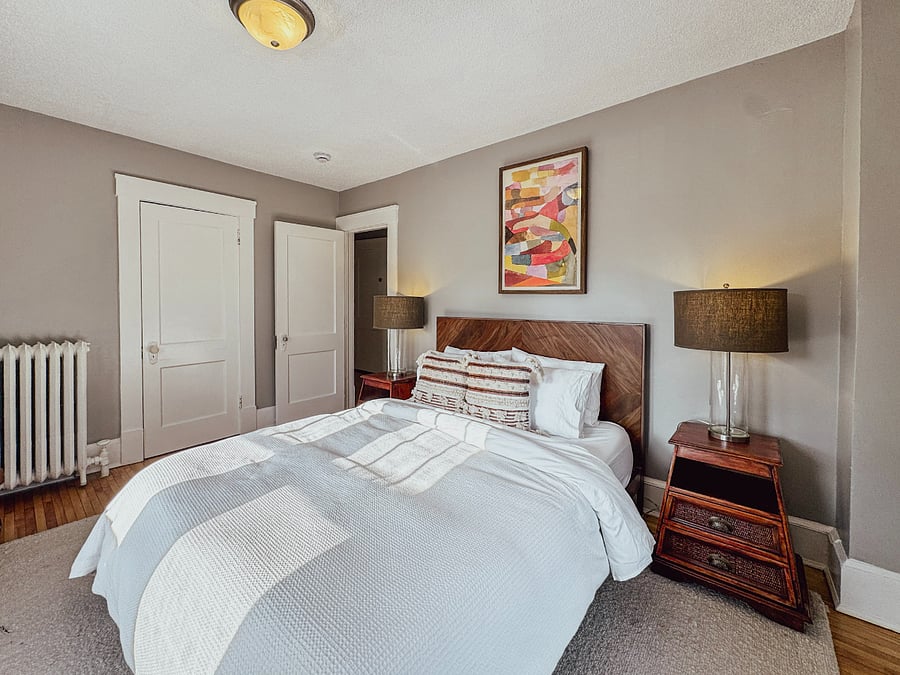 Private queen bedroom with organic linens, blackout window coverings, closet storage, bedside lighting, a cozy bathrobe, and convenient bedside phone charging.