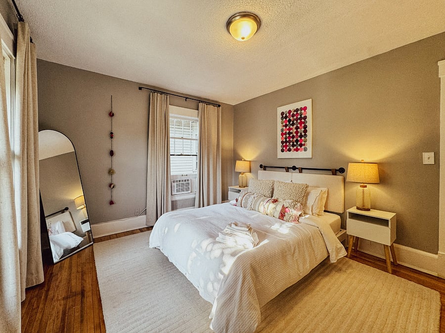 Private queen bedroom with organic sheets, a supportive mattress, blackout window coverings, closet storage, bedside lamps, a bathrobe, and phone chargers conveniently located near the bed.