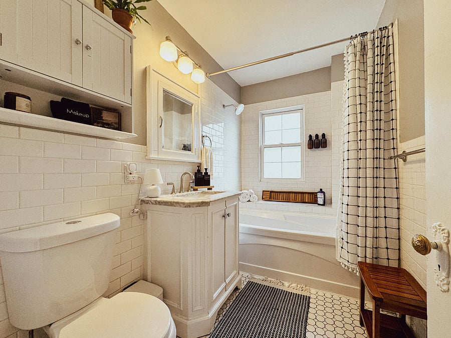 The upper-level full bathroom includes a bathtub and shower, fresh towels, Public Goods toiletries, a hair dryer, and space for everyday essentials.