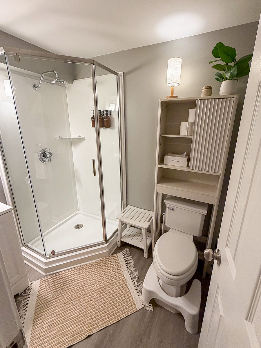 The lower-level full bathroom includes a walk-in shower, fresh towels, Public Goods toiletries, a hair dryer, and convenient access from the theater and game room.