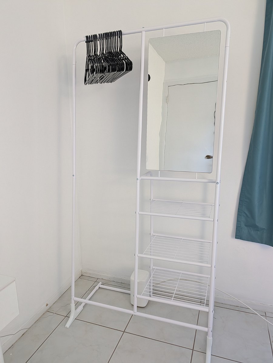 Mirrored wardrobe stand with wire shelves.