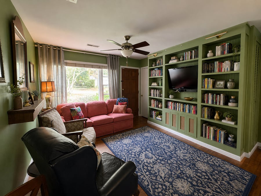 Living room with custom built-in bookcase and comfortable, welcoming furniture with a large picture window looking out over the front yard.