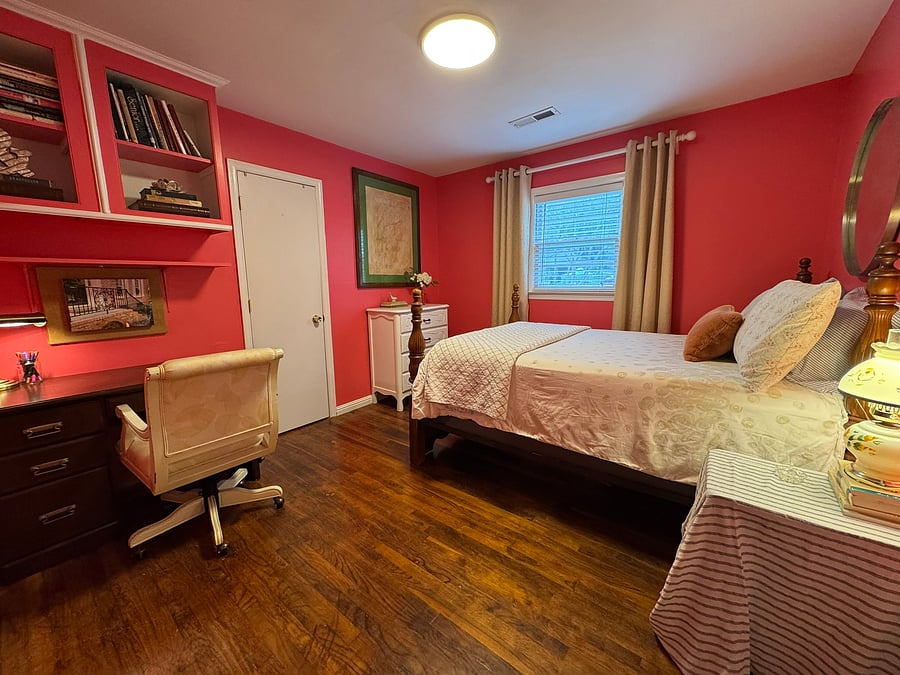 The cheerful 3rd bedroom offers a desk and comfortable rolling chair for work, four poster bed, dresser, and closet.