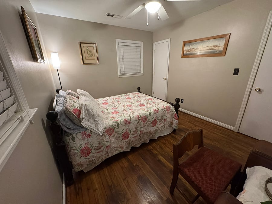 The second bedroom is quiet and relaxing, with freshly painted khaki walls and a midcentury vanity with curved mirror. Has two windows and a closet in the corner.