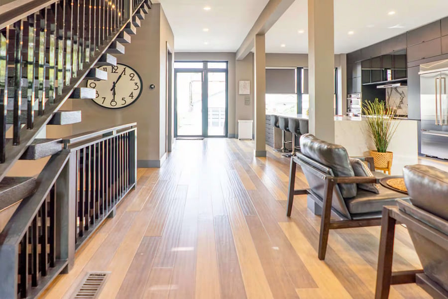 Living seating flows toward the kitchen island beside the modern open staircase.
