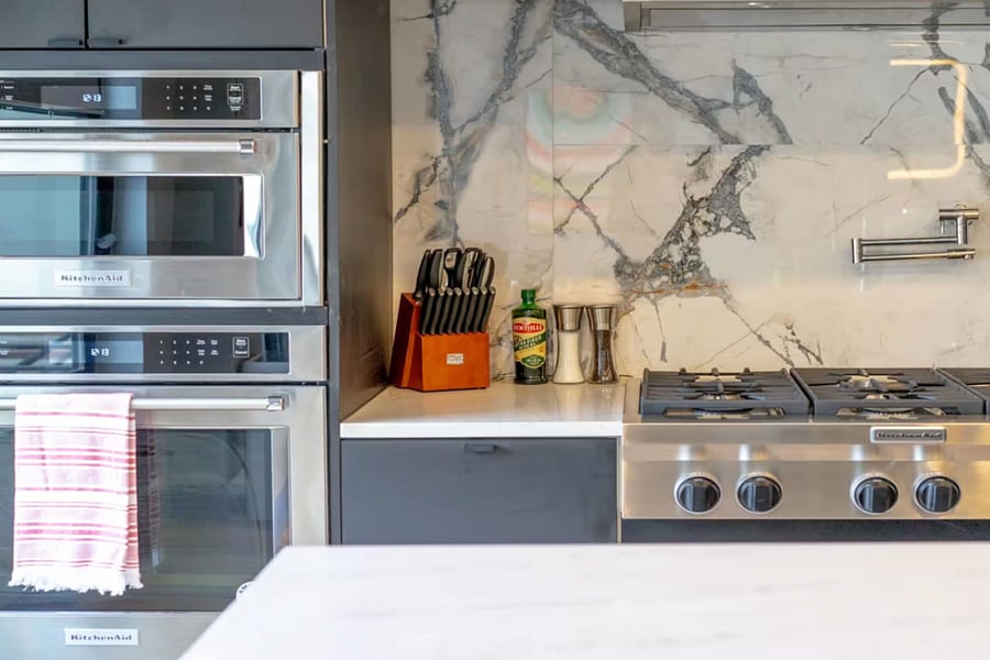 The island sink faces a wall of stainless range, double oven, and refrigerator.