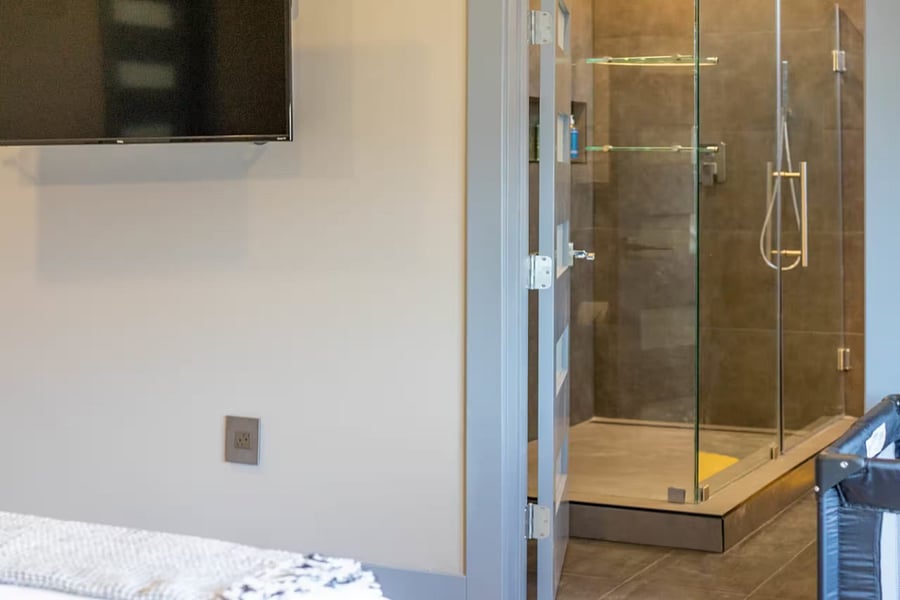 The bedroom faces a wall-mounted TV with an open doorway into the ensuite.