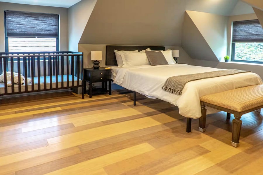 A nursery crib tucks under the sloped ceiling beside the neatly made bed.