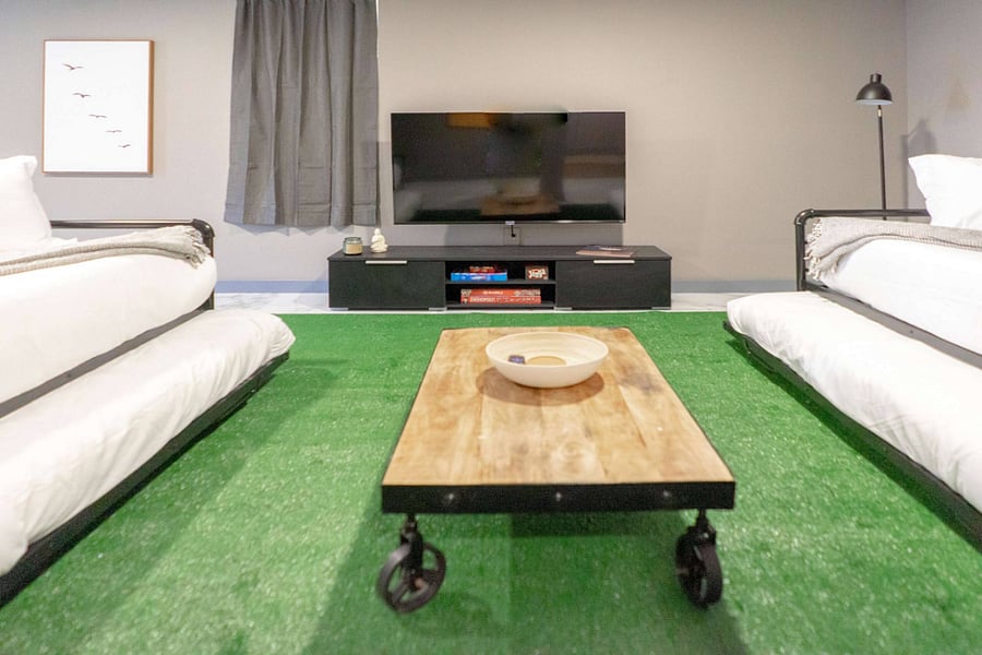 Downstairs, a finished lounge mixes marble tile floors with a green turf seating area.