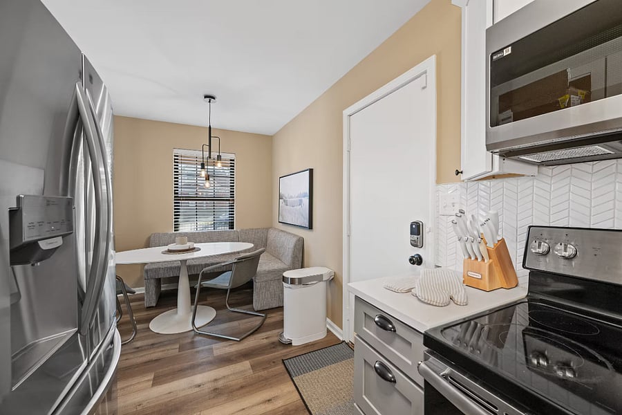 An open dining nook and media wall connect the living area to a bright hallway.