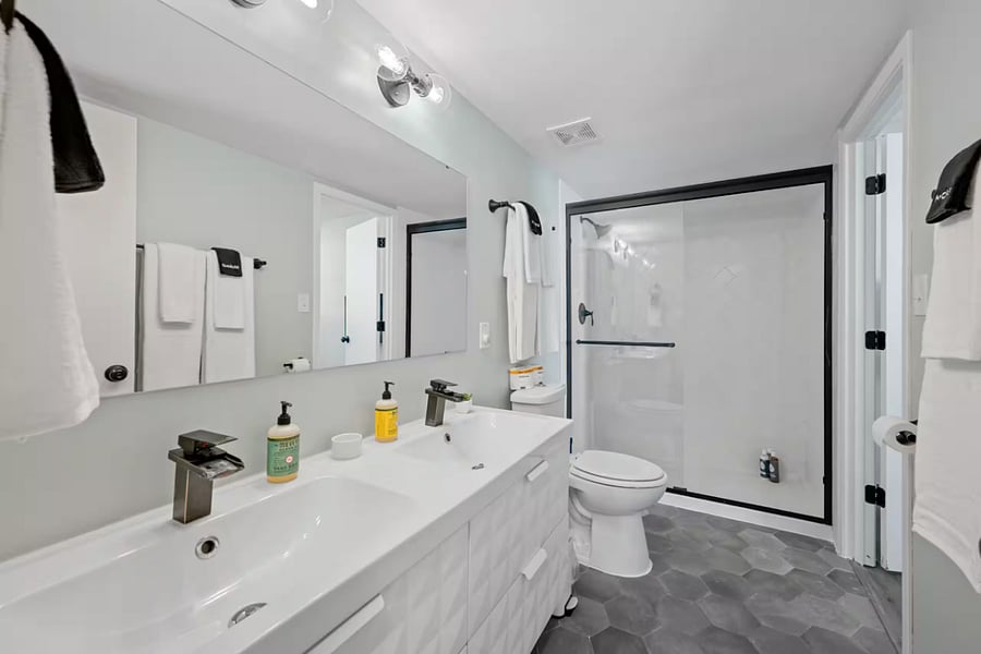 Enjoy a spacious double vanity and a sleek black-framed glass walk-in shower.