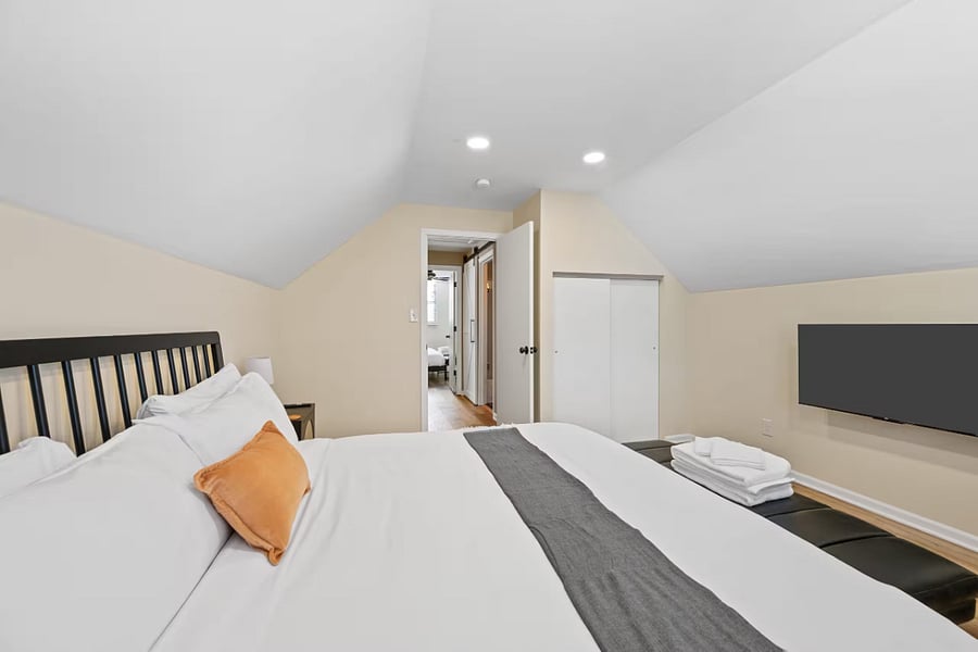Another upstairs bedroom features a black-slat headboard and wall-mounted TV.