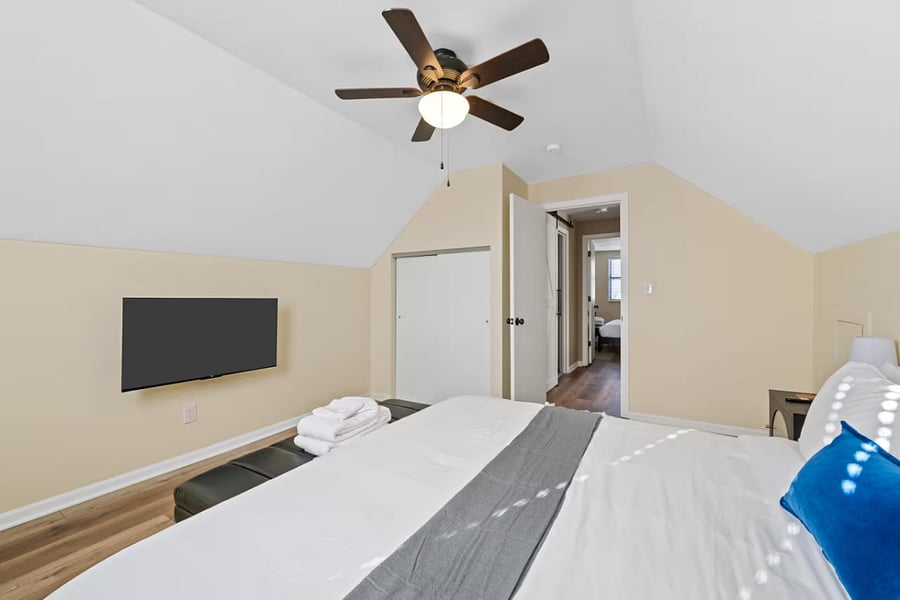 Stocked linen closet shelves sit just outside this tidy upstairs bedroom.