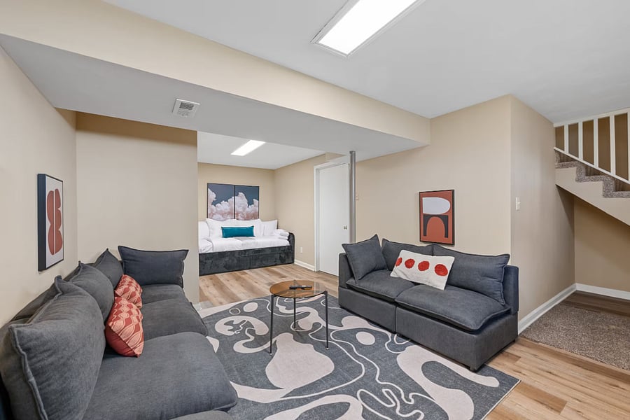 The finished basement offers two sofas, a daybed alcove, and stairs up.