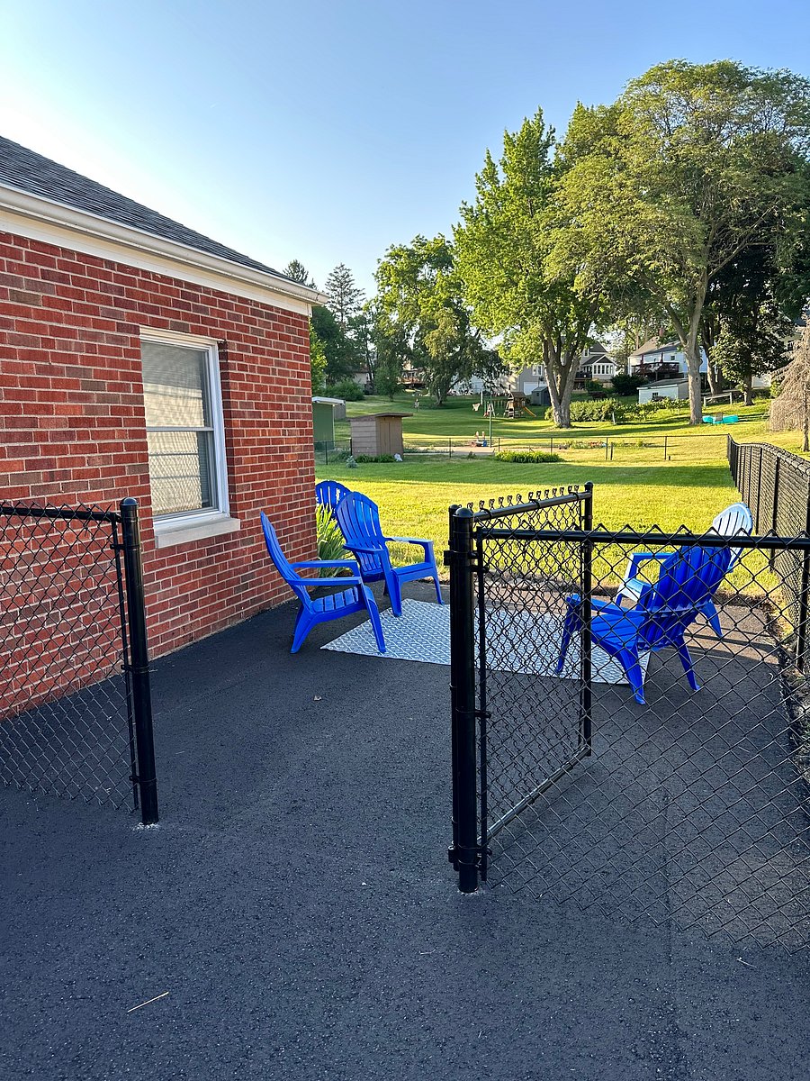 Driveway continues to a fenced patio and huge, flat back yard.