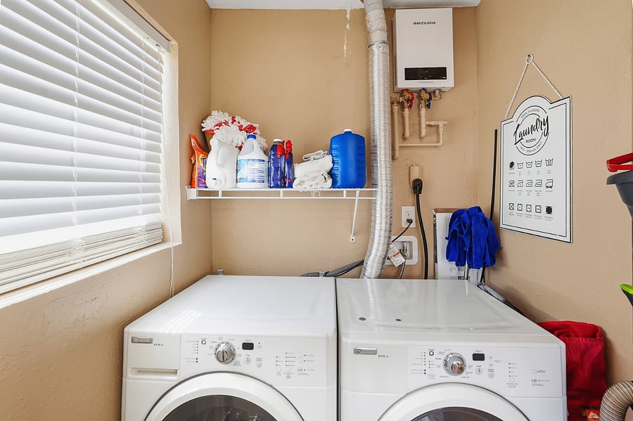 Full Size Maytag Washer and Dryer ideally located in its own laundry room within the kitchen area, with natural light and opaque glass doors that allow additional natural light into the kitchen.
