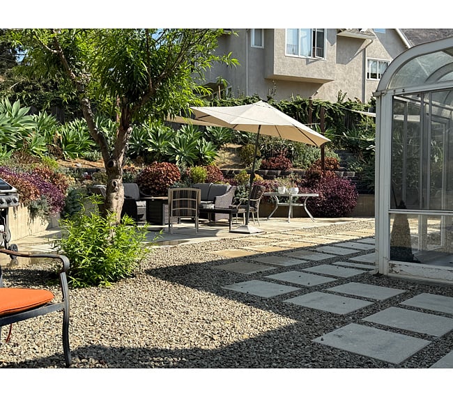 Just off the sunroom, you'll find the back yard, hillside terrace, and patio area. Yard features modern paver/stone layout with cushioned seating, shade umbrella, shade sails, small fountain for the birds and succulents. Yard maintenance is included. This is a shared space. Fully fenced.