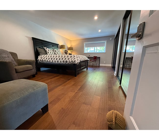 Master Suite Sanctuary: Generously sized bedroom featuring mid-century modern furnishings, a dedicated remote workspace, and direct ensuite access. Dimensions: 11' 8" x 18' 3" (200 sq. ft.) + large closet/storage.