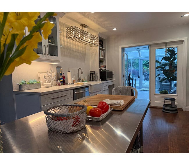 Sink, drawer dishwashers, microwave, cookbooks. Stainless prep table. French doors at end of kitchen open to glass, screened sunroom. This is a shared space.