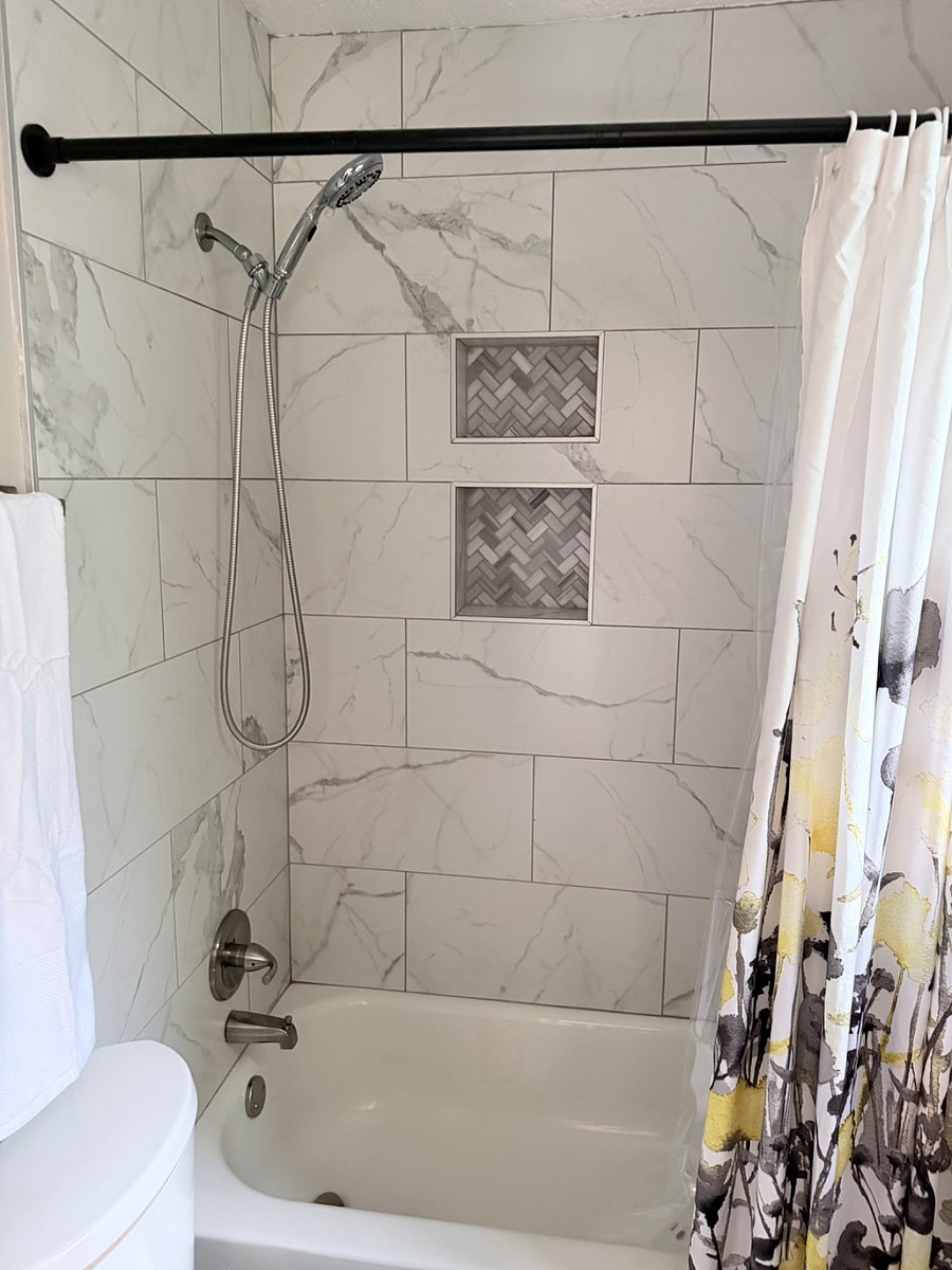 Updated tiled tub/shower with handheld showerhead and built-in niches