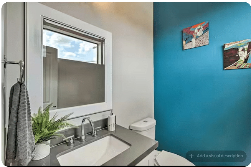 Modern bathroom with a sleek vanity, large mirror & contemporary fixtures.
Bold blue accent wall and colorful artwork add personality.
A high window brings in natural light while maintaining privacy.