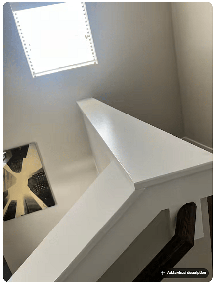 Multi-level stairway with crisp white railings and modern finishes, highlighting the homes vertical layout.
A large upper window brings natural light into the stairwell, while contemporary wall art adds visual interest.