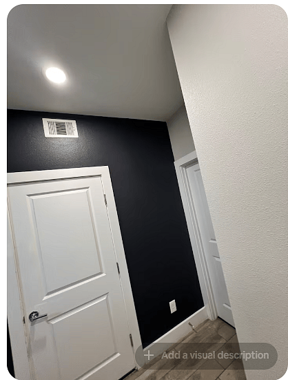 Clean interior hallway with modern white doors, crisp trim & a bold dark accent wall. Recessed lighting keeps the passage bright, while neutral tile flooring provides a polished transition between rooms.
