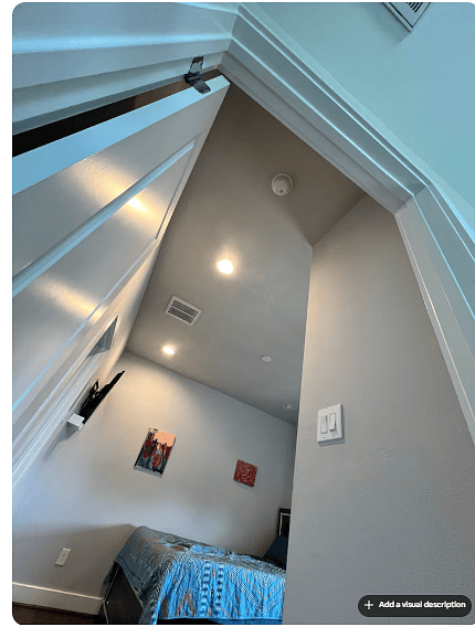 Cozy bedroom with high ceilings, warm wood floors & modern recessed lighting.
A wall-mounted TV and colorful artwork add comfort and personality, while the open doorway highlights the rooms easy connection to the hallway.