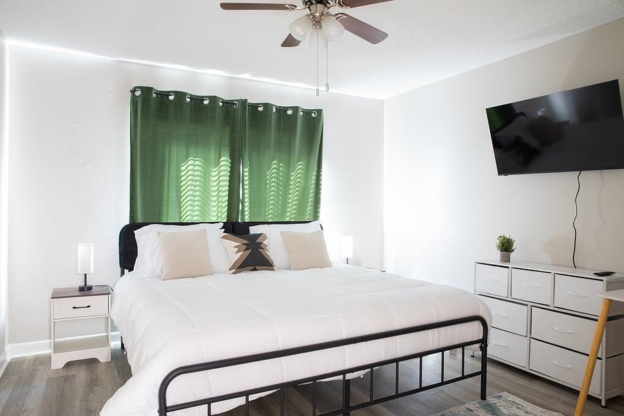 Bedroom 1: A cozy first bedroom featuring a comfortable bed, crisp white bedding, and a wall-mounted TV for relaxing evenings.