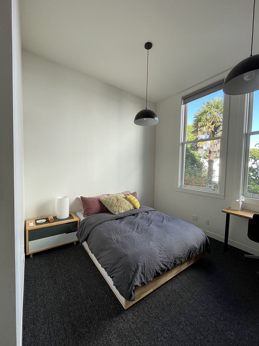 New queen size bed with drawers, where extra bed and bath linens, hair dryer, vacuum, iron and ironing board, and extra blankets are stored. Generous windows with room-darkening shades look out over the rear garden.