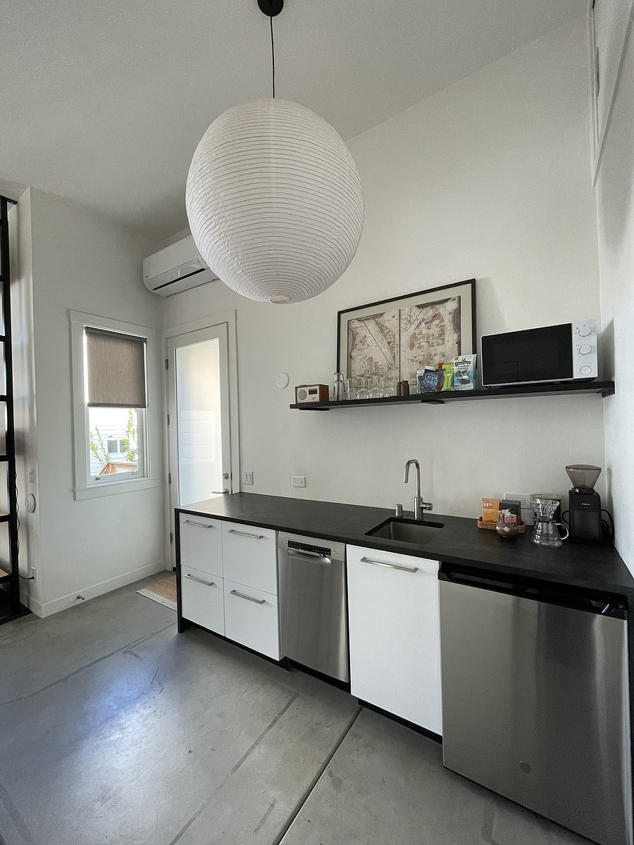 Looking toward entry door. Drawers contain dishes, flatware, pots, cooking tools, canned food storage and induction cook top. Dishwasher and refrigerator below, with microwave above. If you're a coffee lover, there's a grinder and pour-over kettle.