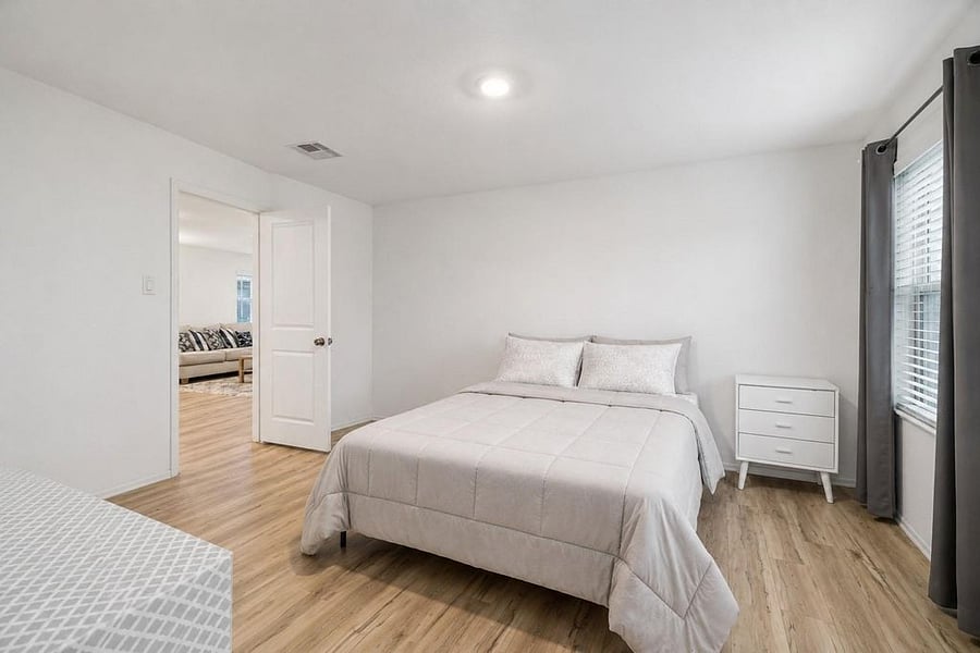 Spacious primary bedroom, fully furnished with walk-in closet and private bathroom. View towards living room area. (sheets & covers may vary)