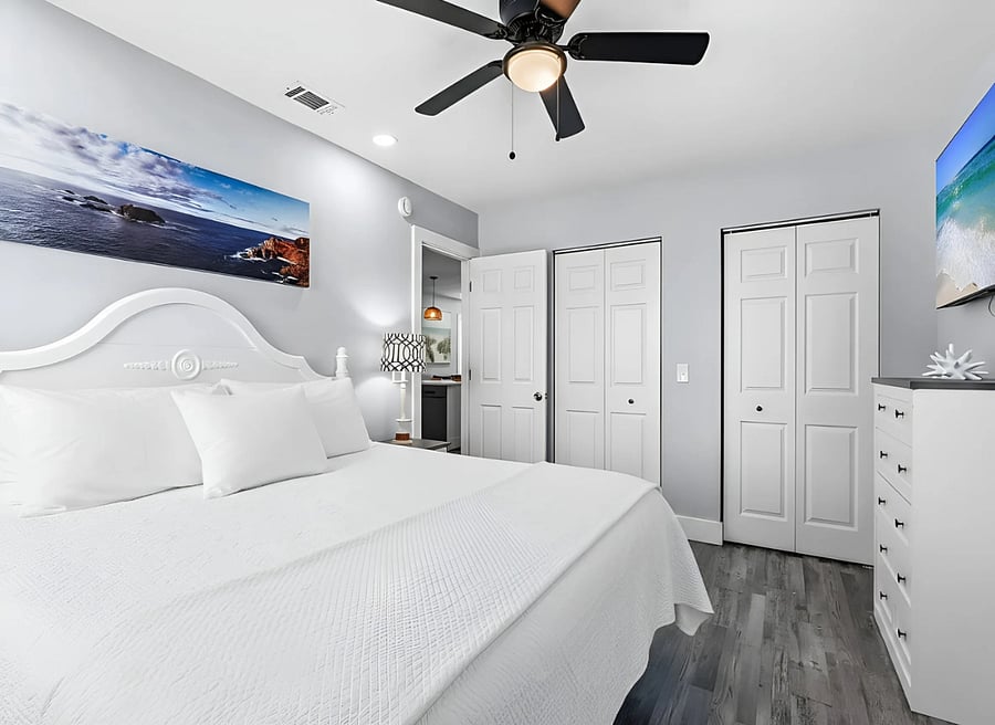 Private primary bedroom with comfortable king-size bed, ceiling fan, storage and Smart TV