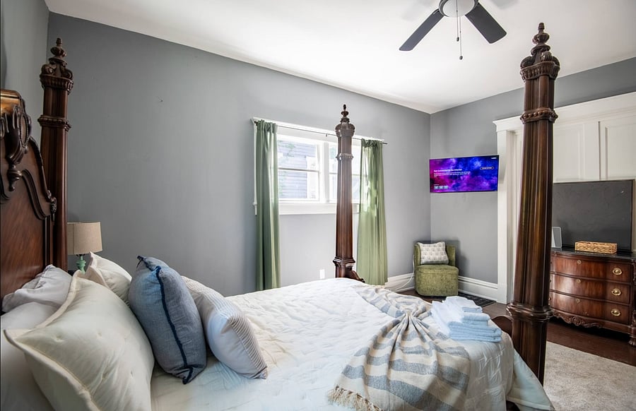This inviting bedroom combines classic charm with modern comfort. A small seating nook adds a perfect touch for downtime.