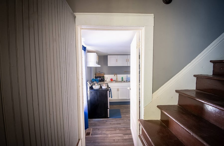 Step into a cozy entryway with a view of the kitchen and a unique glimpse of the home's original staircase.