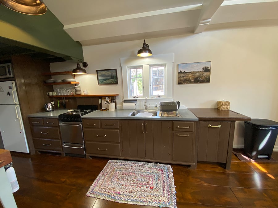 The kitchen with the refrigerator to the left, counter space, a stove/oven, sink, dishwasher. 