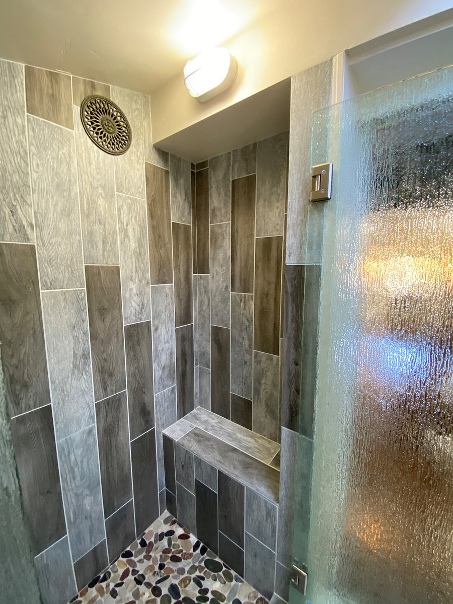 The shower has vertical porcelain tiles with storage for shampoo, etc. 