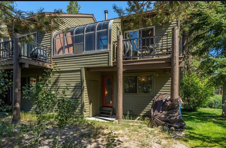 Back entry with wood storage and view of second-story solarium and outdoor patio