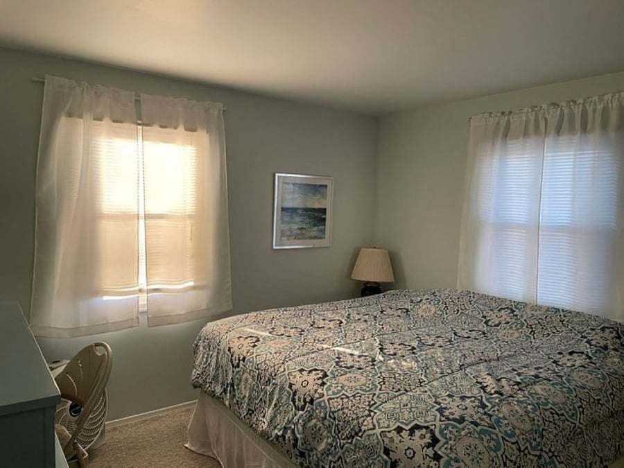 King bedroom with closet, two dressers, work station, fan, two nightstands, and lamps.