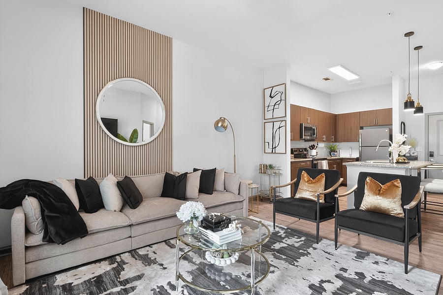 The spacious open-concept living room is anchored by a striking custom wood slat feature wall, 65in smart tv, a plush designer sectional sofa layered in rich textures, and elegant velvet accent chairs touched with curated art to complete the space!