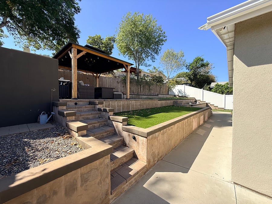 Tiered backyard with one level of astro turf and then real grass on the upper level. Fully furnished patio under the wooden gazebo.