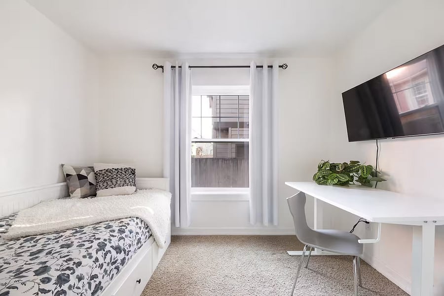 Small bedroom with twin bed, standing desk, chair, TV and closet on the first floor