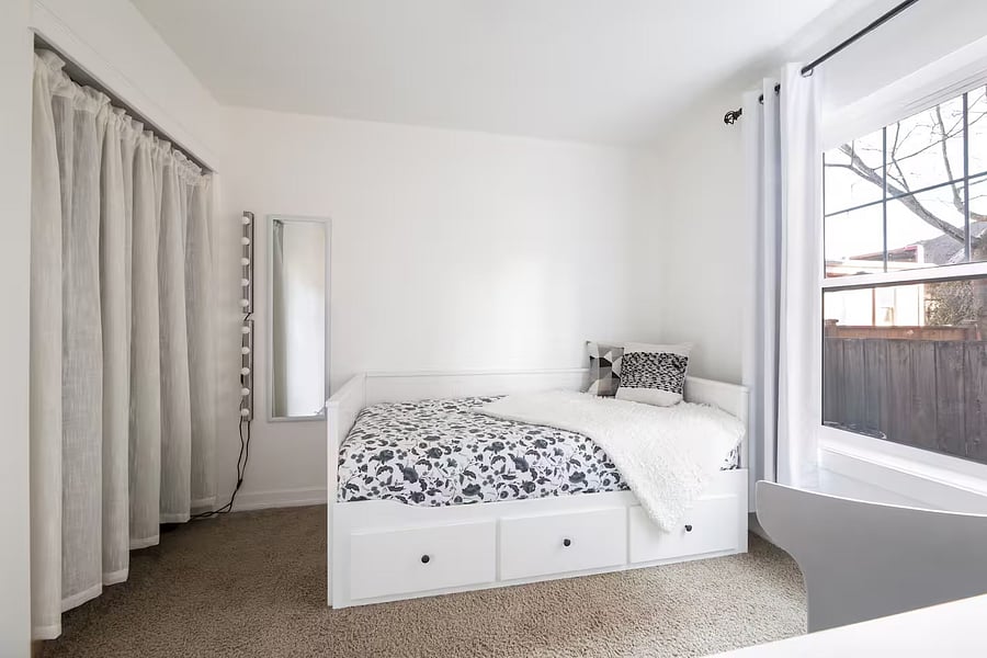 Small bedroom with twin bed, standing desk, chair, TV and closet on the first floor