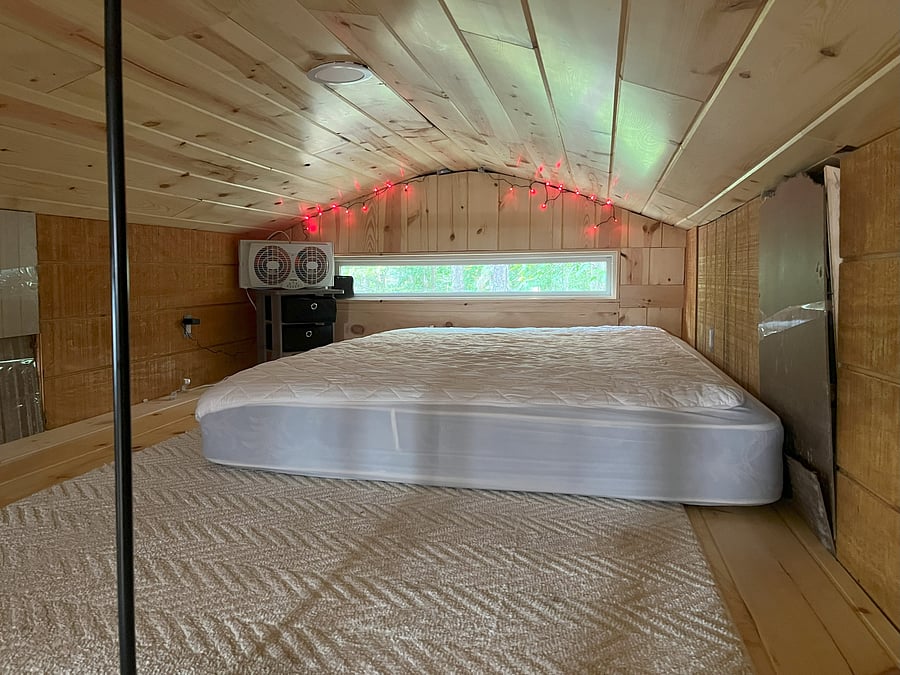 Sleeping loft with queen mattress. Head room only. Look out into the tops of the trees.