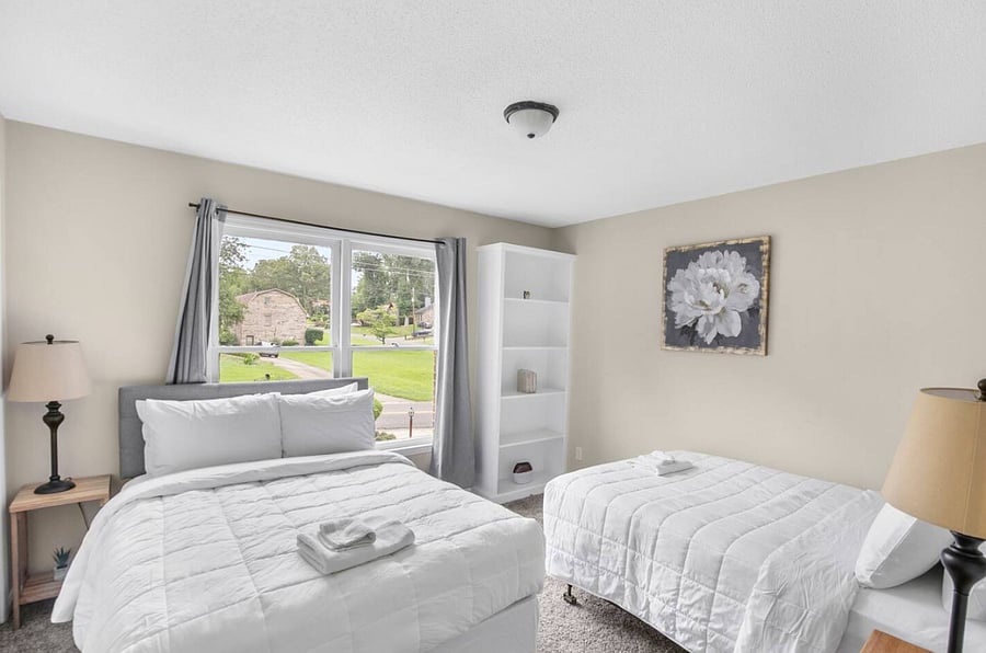 This bedroom offers a versatile setup with both a queen and a full bed, creating a comfortable space that works well for a variety of guests while still feeling relaxed and thoughtfully arranged.